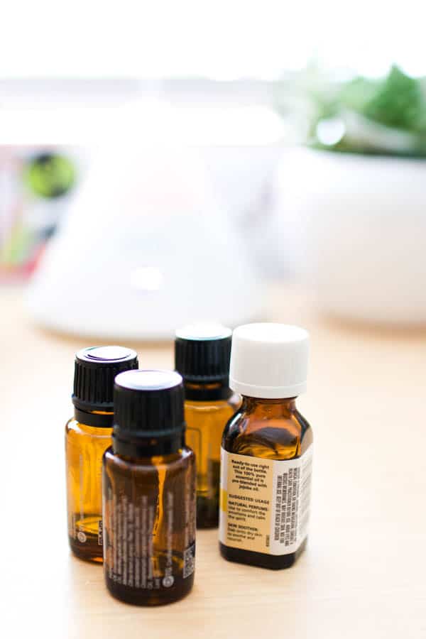 Bottles of essential oils on a table with a diffuser blurry in the background