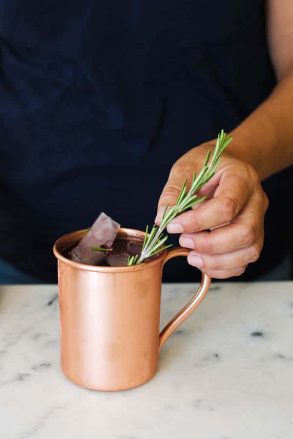 Adding rosemary garnish to a Halloween Moscow Mule.