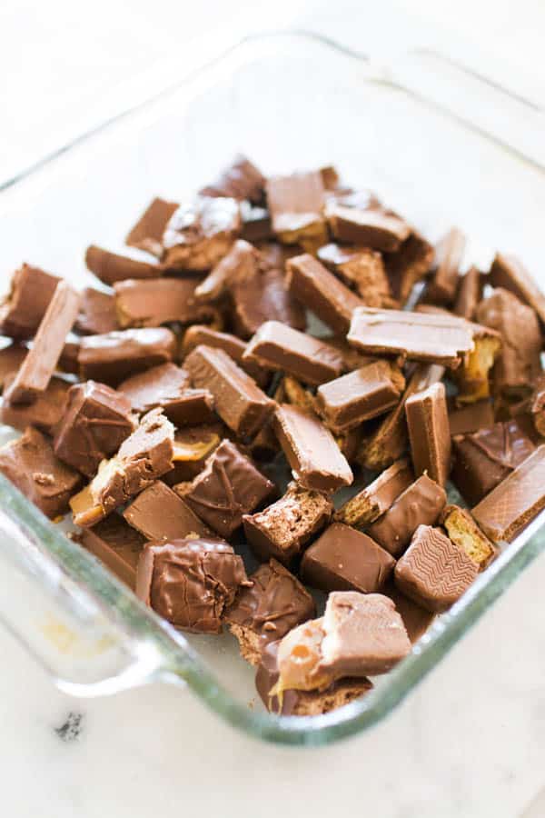 Chopped up fun sized candy bars in a glass baking dish.
