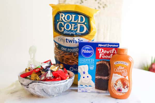 Ingredients for halloween dump cake - fun sized candy bars, pretzels, boxed cake mix and caramel sauce. 