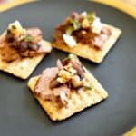 Close up of a Triscuit appetizer with flank steak and blue cheese on a plate.