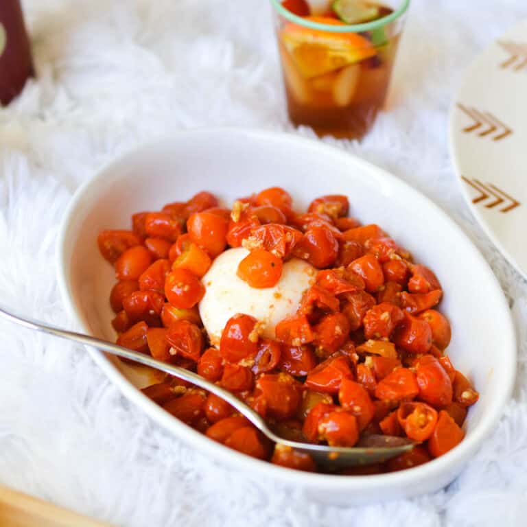 Close up of a Burrata Appetizer in a serving dish with roasted cherry tomatoes.
