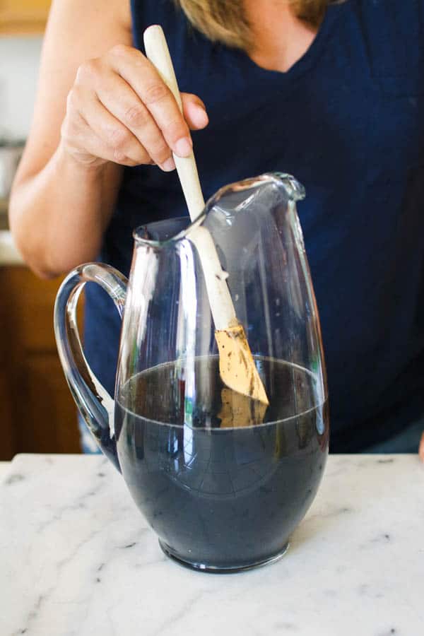 Black citrus vodka punch recipe being stirred.