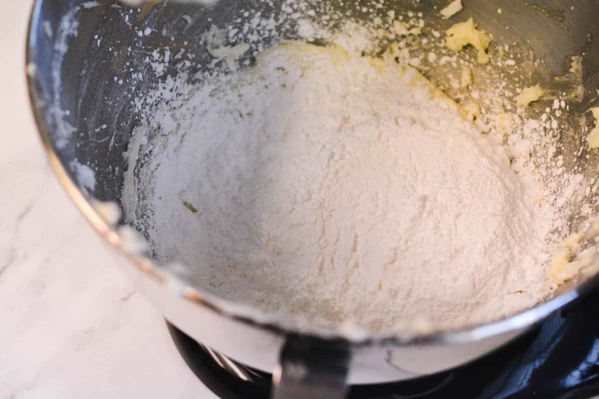 The bowl of a stand mixer with powdered sugar and butter.