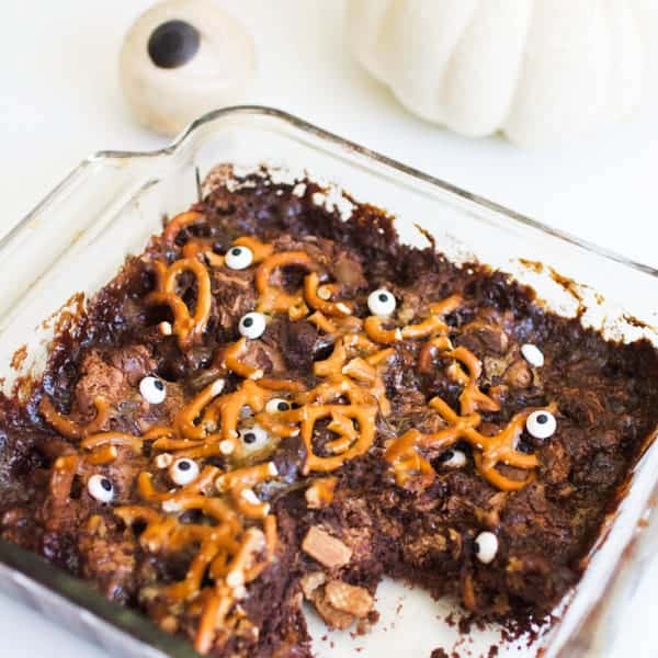 A dump cake with chocolate cake mix for halloween topped with pretzels and candy eyes.