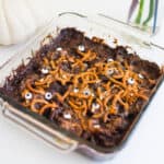 Halloween dump cake topped with pretzels and candy bars in a glass dish.