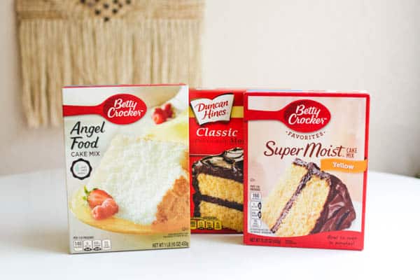 yellow, chocolate and angel food cake mix boxes sitting on a table. 