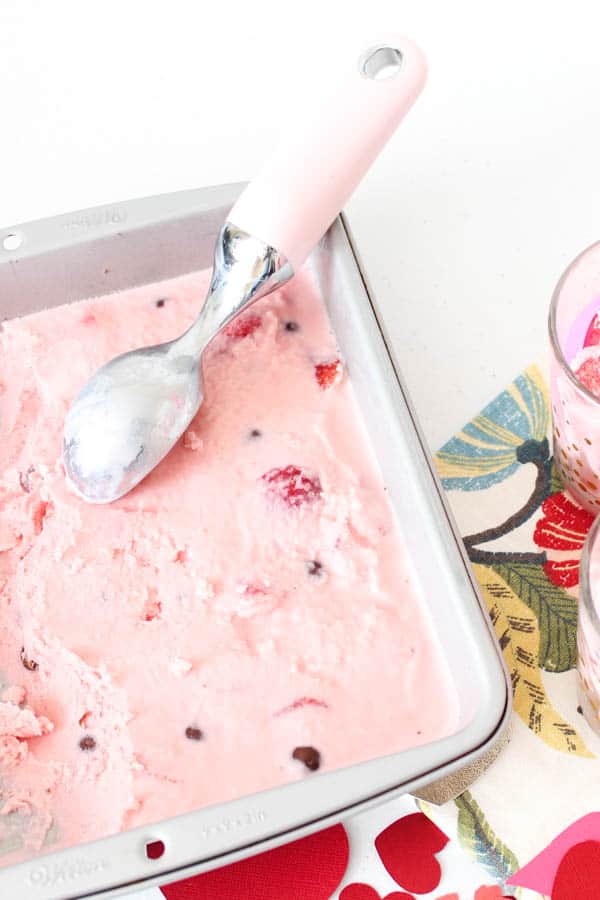 strawberry ice cream with M&Ms, frozen strawberries and condensed milk in a pan with ice cream scooper