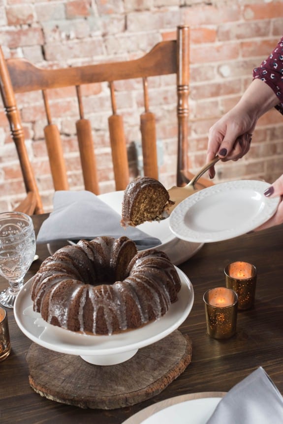 Woman taking a piece of nutmeg bundt cake sliced with cream cheese drizzle.