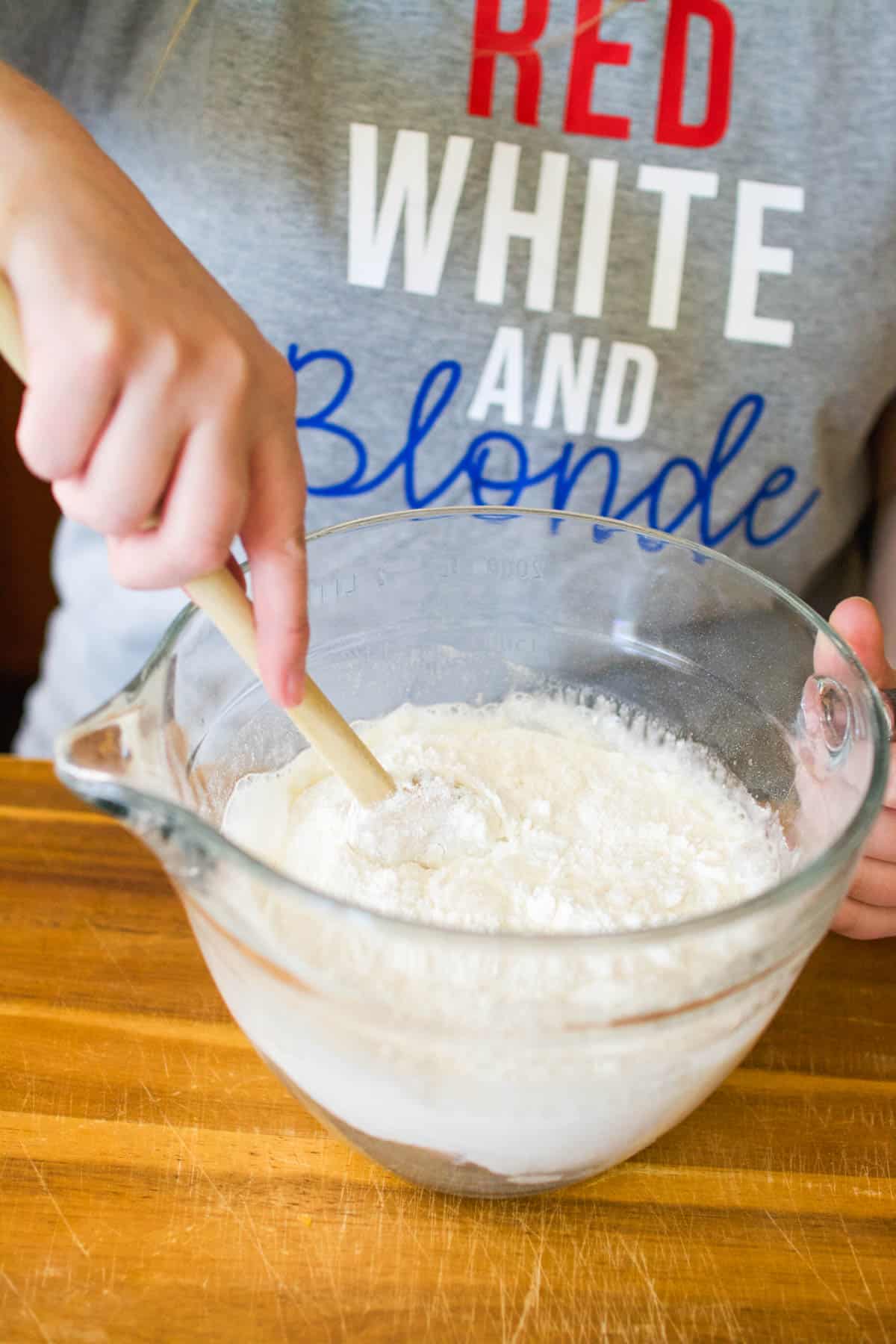 A woman mixing angel food cake mix and water in a mixing bowl.