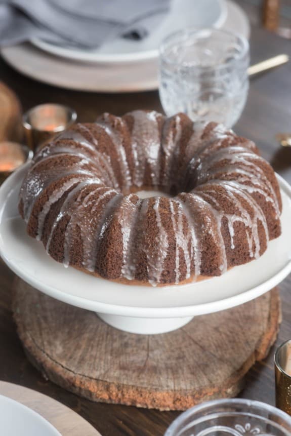 An icing covered nutmeg bundt cake on a white plate. 
