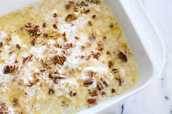 Pumpkin dump cake with pecans and toffee bits covered in melted butter.