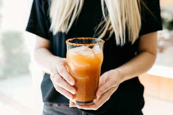 Easy and delicious pumpkin michelada being held by a woman.