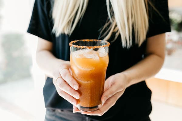 Easy and deliciuos pumpkin michelada being held by a woman.