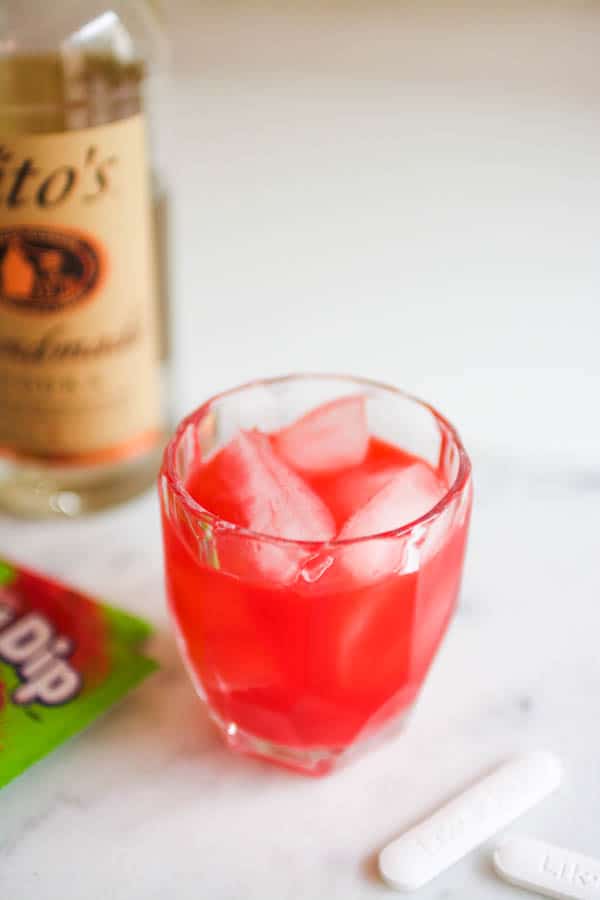 A bright pink cocktail in a short glass on a table. 