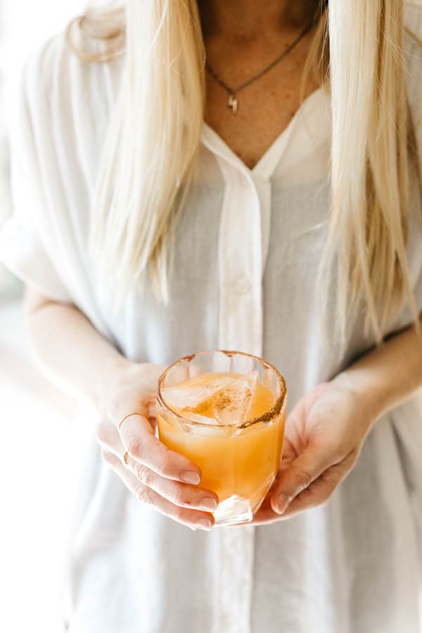 Woman holding fall pumpkin margarita recipe.