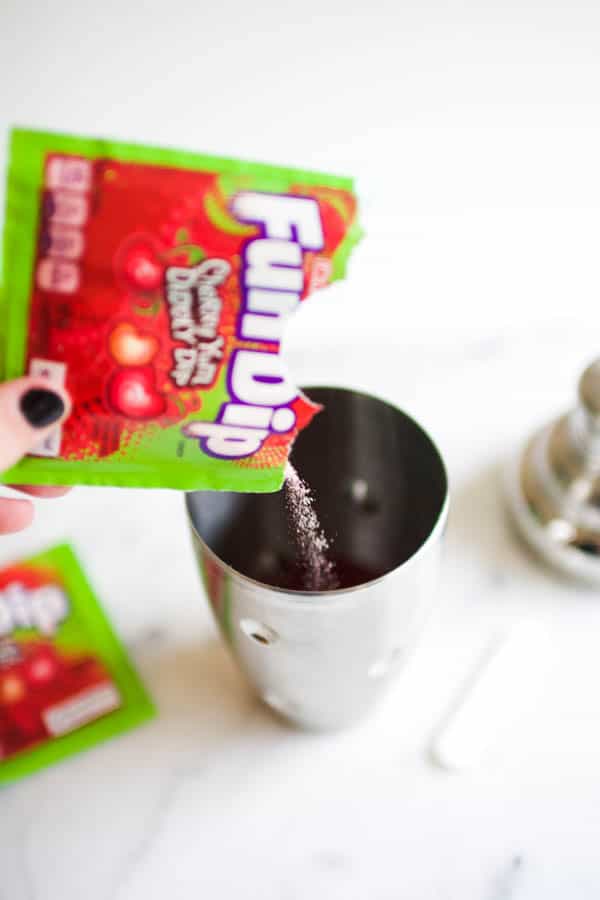 A pouch of Fun Dip candy being poured into a cocktail shaker. 