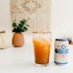 pumpkin michelada on a table next to a can of beer
