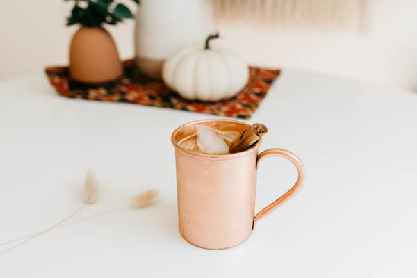 Pumpkin Spice Moscow Mule recipe in a copper cup on a table. 