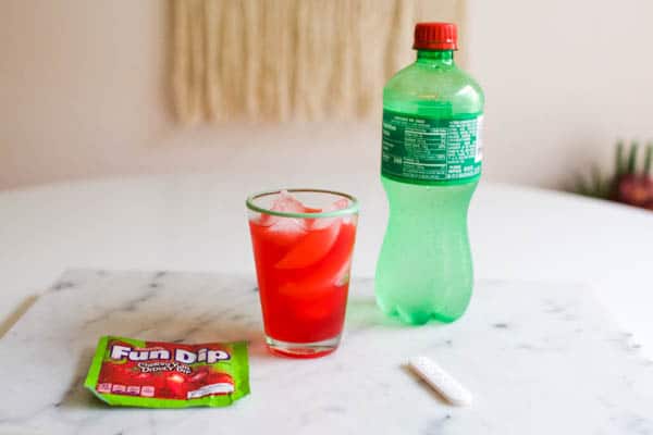 Candy inspired mocktail on a table next to lemon lime soda.