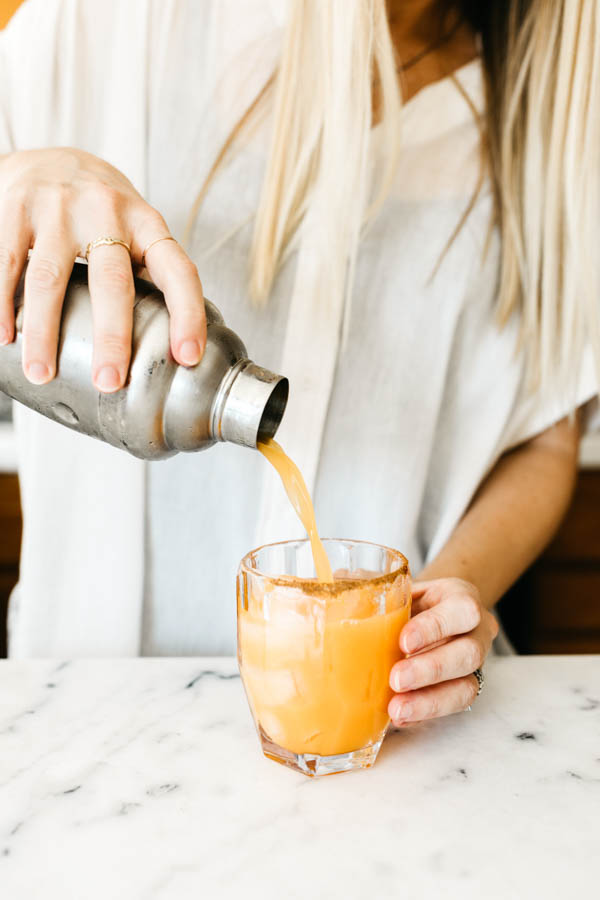 Woman pouring Pumpkin Spice Margarita into a glass. 