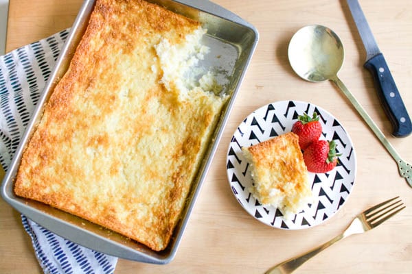 Pineapple Angel Food Dump Cake in a pan on a table with a piece cut out and served on a plate.