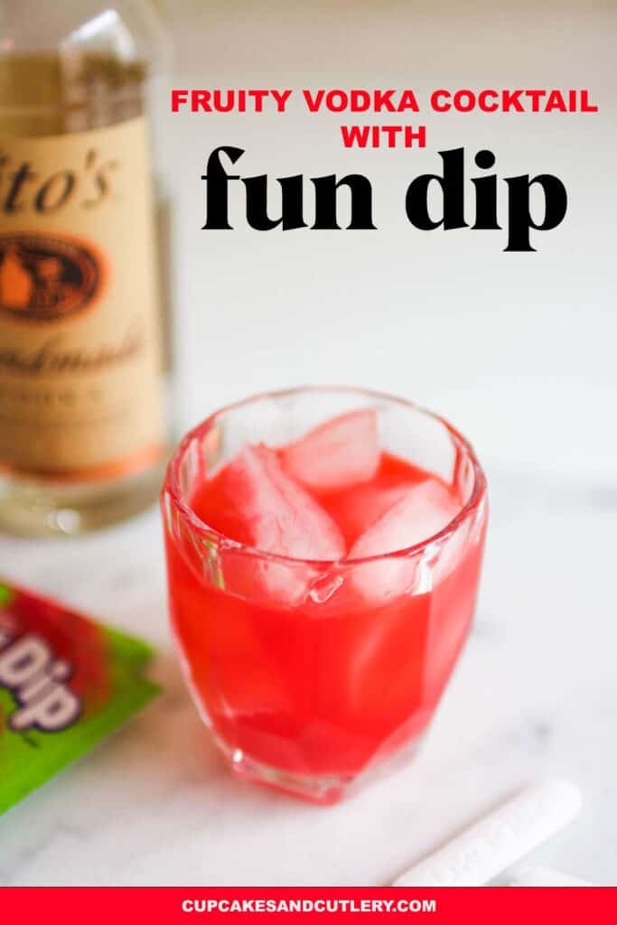 Close up of a pink cocktail in a glass on a table next to a bottle of vodka.