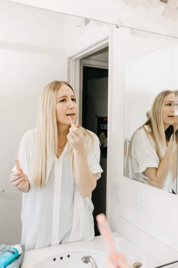 Woman putting on lip gloss.