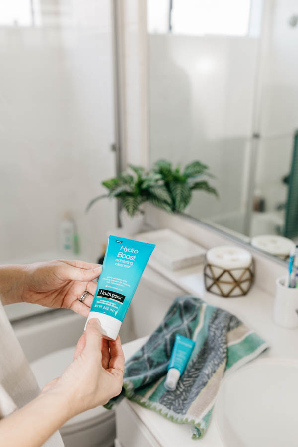 Woman holding a Neutrogena Hydro Boost product in her hand in the bathroom. 