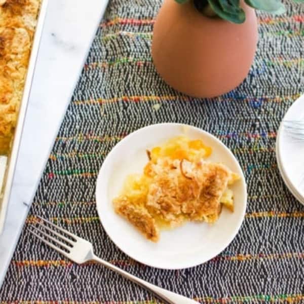 Scoop of orange pineapple dump cake on a plate on a table.