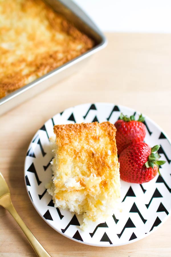 Close up, top down image of pineapple dump cake with angel food cake cut out and served on a dish with fresh strawberries. 