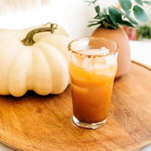 Close up image of a pumpkin michelada in a spice rimmed glass.