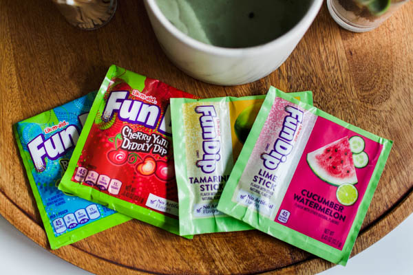 Fun dip candy pouches in a variety of flavors on a wooden tray.