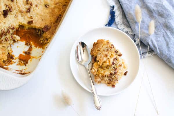 Yummy pumpkin dump cake to make for Thanksgiving on a dessert plate with a spoon. 