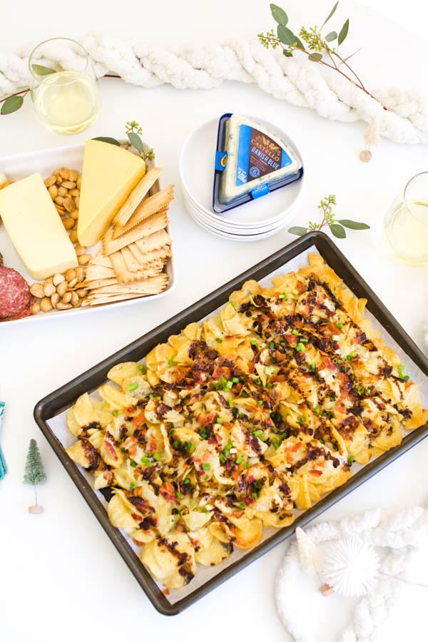 Potato chip nachos with blue cheese sauce on a table.