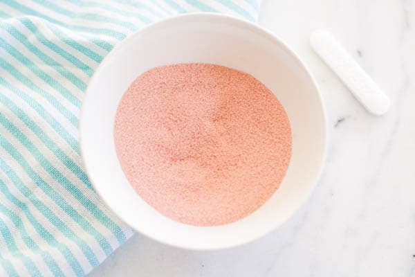 A small white bowl on a counter full of pink powder candy. 