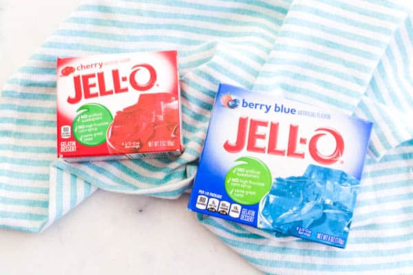 A box of cherry Jello next to a box of berry blue Jello. 