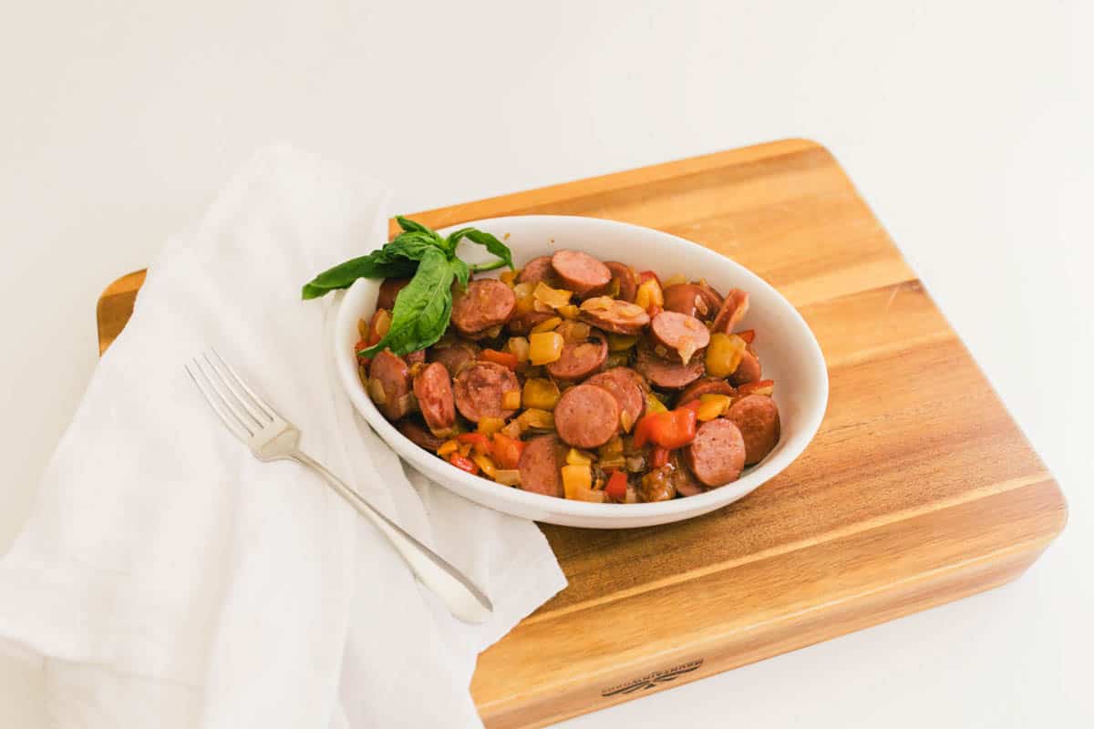 Overhead shot of a sausage bowl served over quinoa with peppers and onions in a serving bowl on a table. 