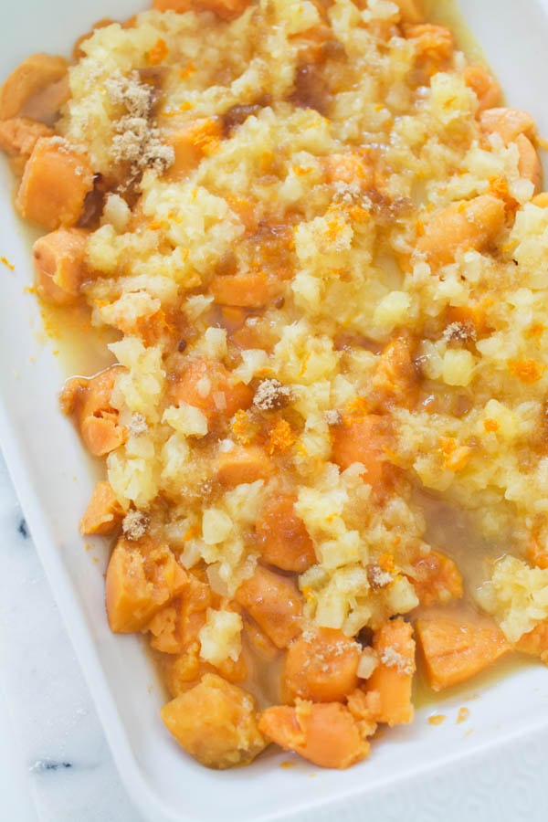 Canned sweet potatoes and crushed pineapple in a baking dish for a dump cake.