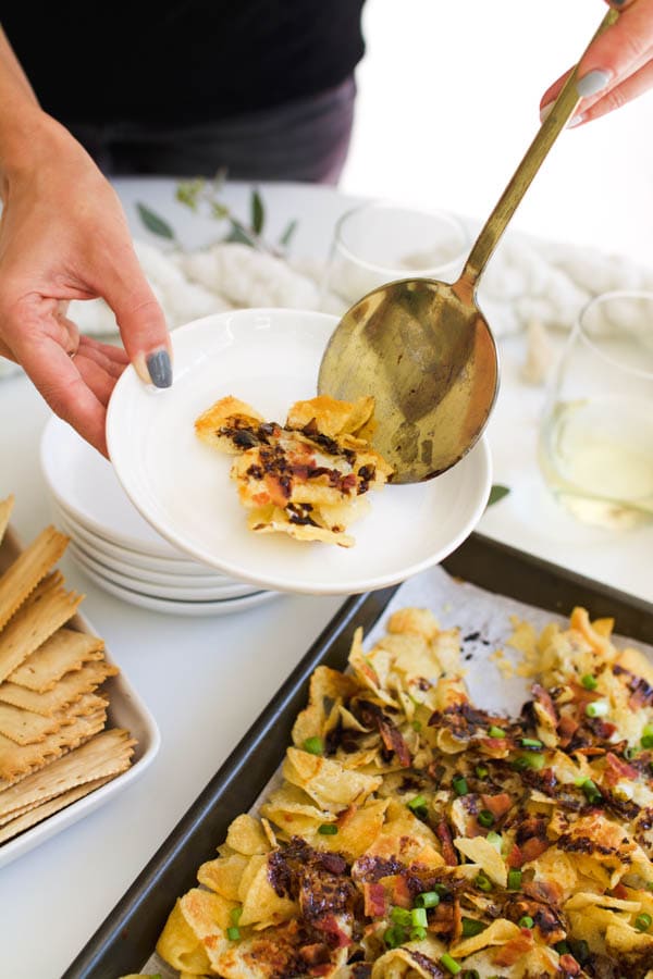 Girl serving herself some Potato Chip Nachos with Blue Cheese Sauce.