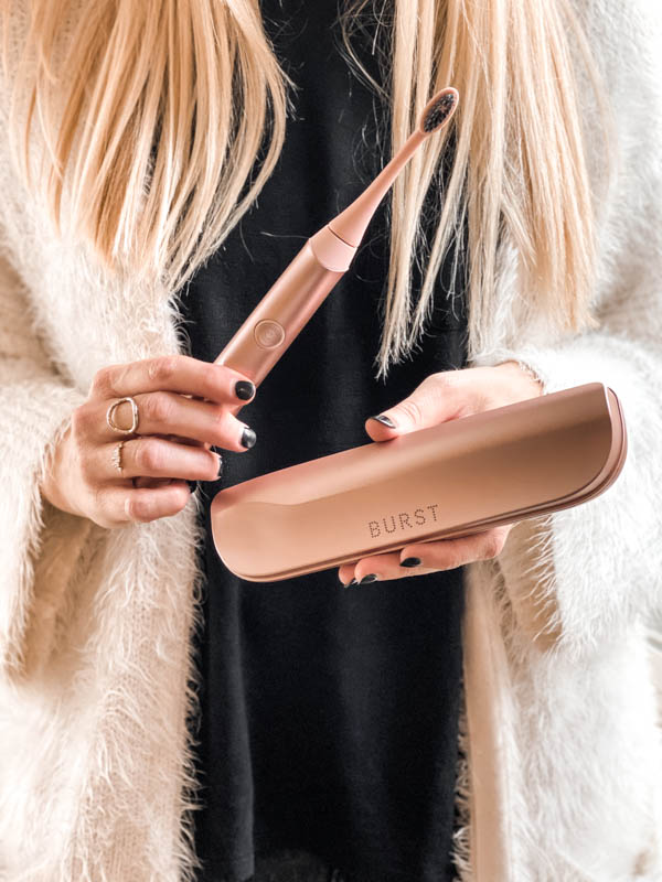 holding a rose gold burst sonic toothbrush in a woman's hand