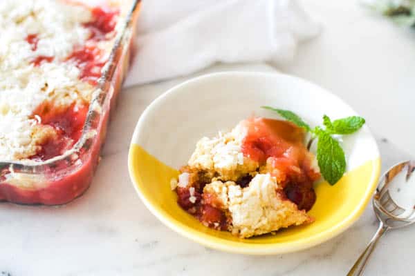 A yellow and white bowl with a serving of Microwave Dump Cake with cherries. 