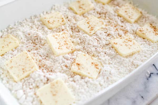Eggnog dump cake being made with butter pats on the unbaked dessert.