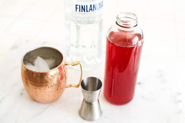Copper mule mug next to cranberry juice and jigger.
