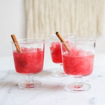 Square image of three small parfait glasses filled with cranberry vodka slush.