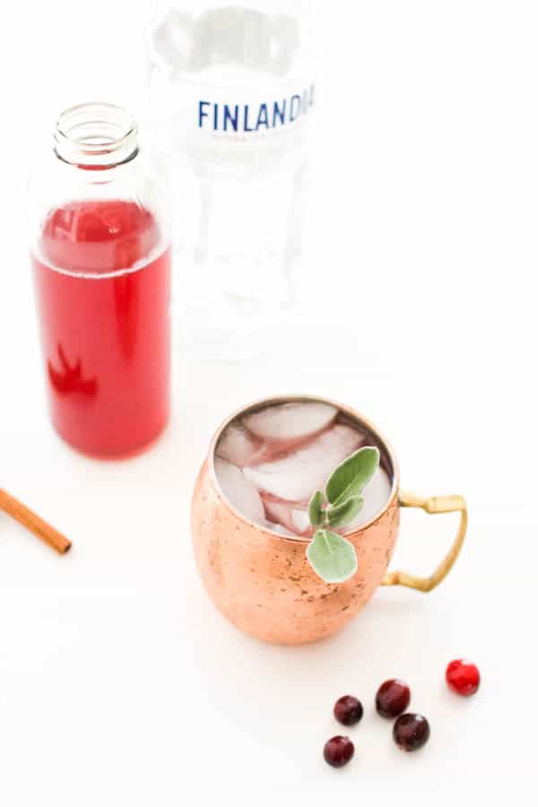 Overhead shot of a Spiced cranberry mule on a table in a copper mug next to a bottle of cranberry juice.