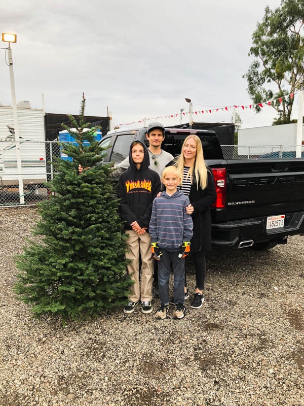 Family standing by a Christmas tree and a truck.