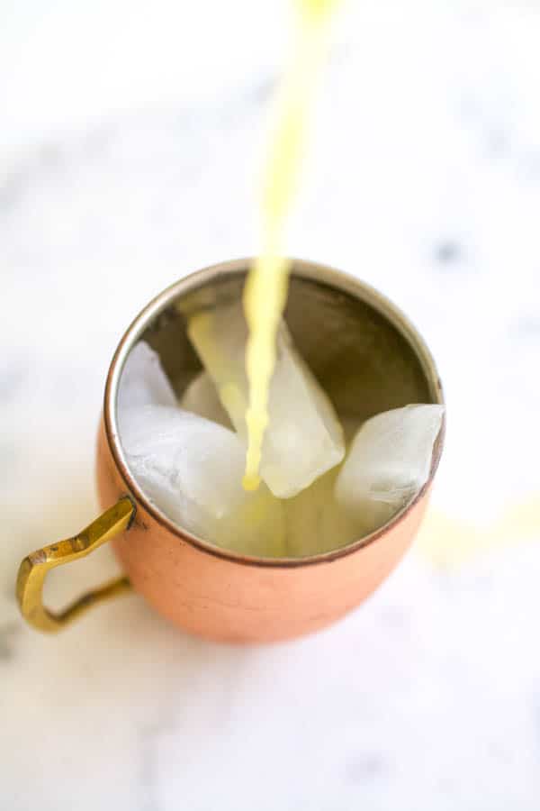 pouring orange juice into a copper moscow mule mug