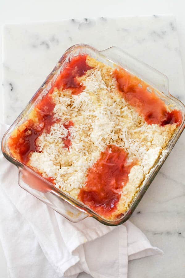 Overhead view of a microwave dump cake made with cherry and pineapple and topped with cake mix and coconut.