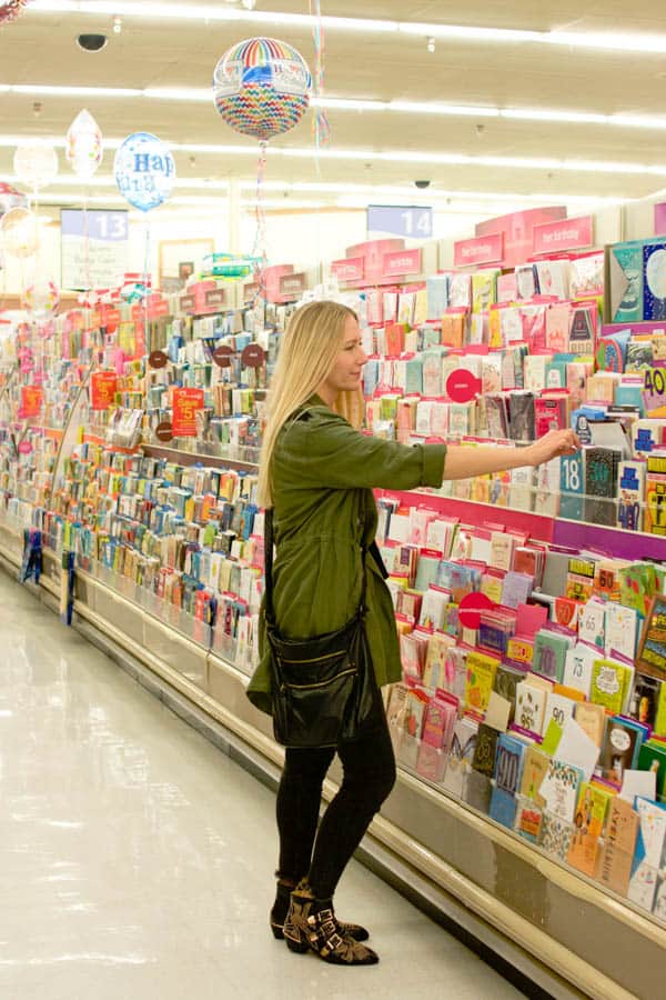 Woman shopping for greeting cards in a grocery store.